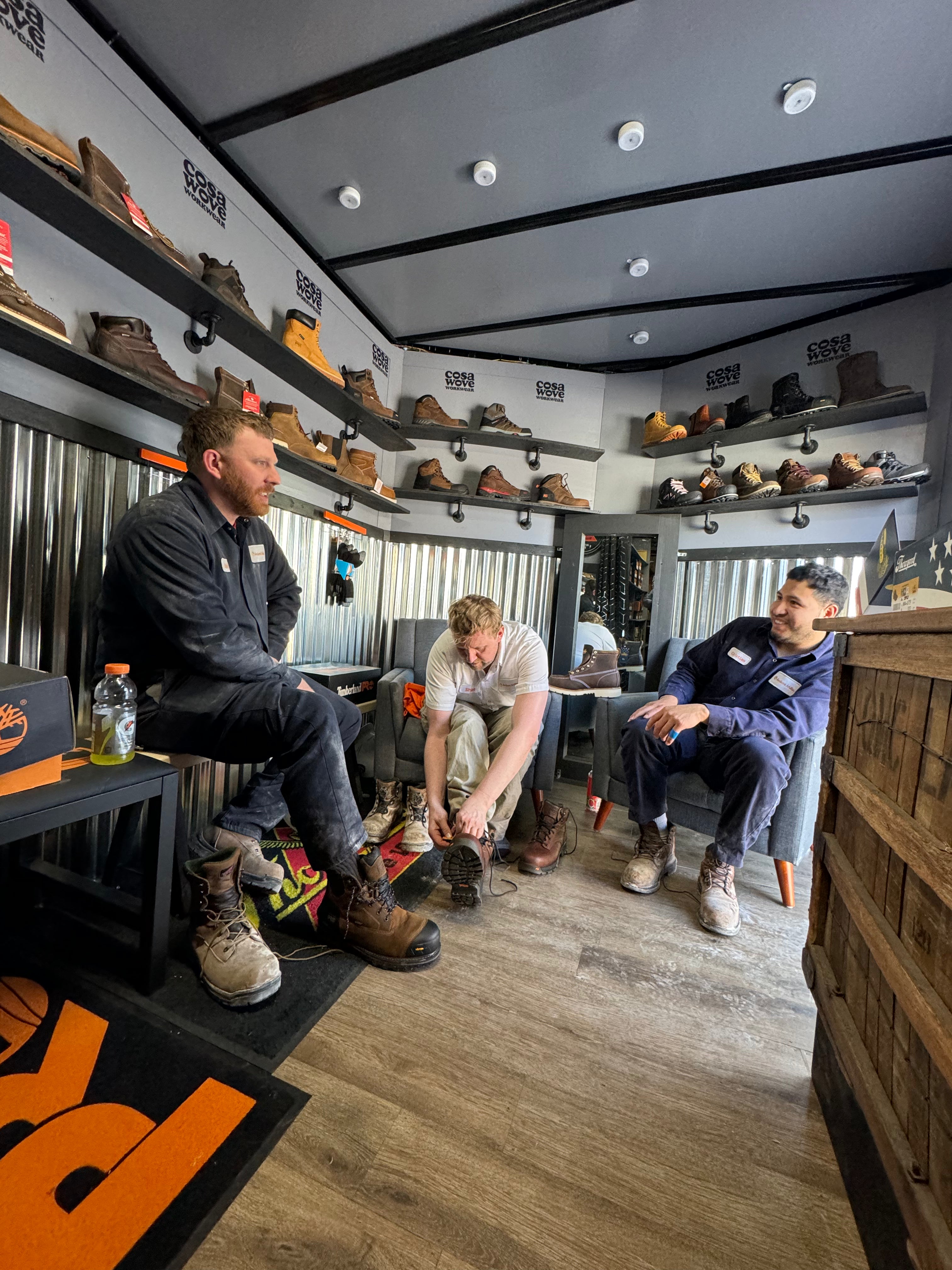 Three men in a room with shelves of shoes and Cosawove branding.